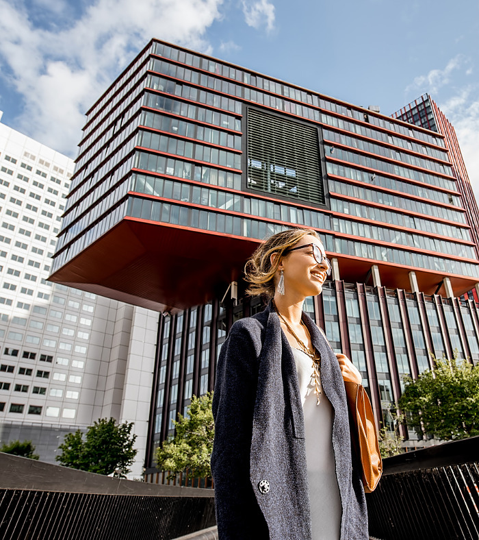 Lifestyle portrait of a young woman walking the bridge at the modern district with slyscrapers in Rotterdam city