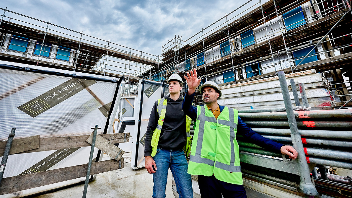 Aannemer en bouwvakkers lopen over de bouwplaats van een nieuw bedrijfspand en bekijken en bespreken de isolatie