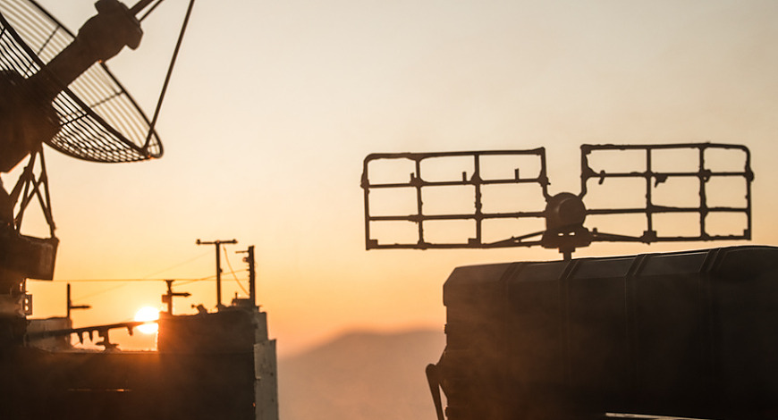 Creative artwork decoration. Silhouette of mobile air defence truck with radar antenna during sunset. Satellite dishes or radio antennas against evening sky. Selective focus