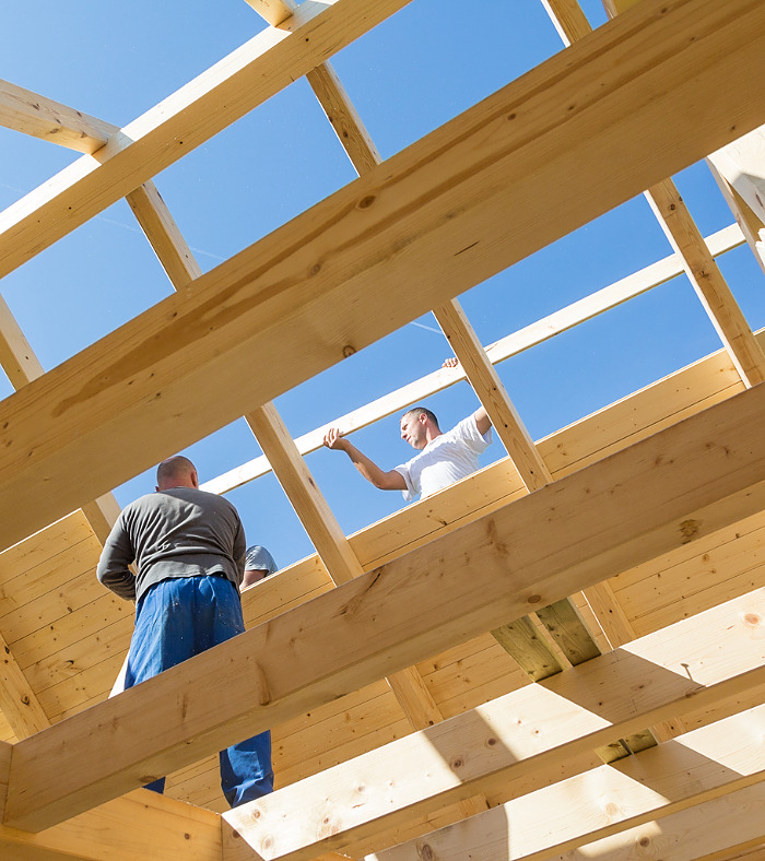 Roof builders mounting prefabricated wooden roof construction. Construction industry concept.