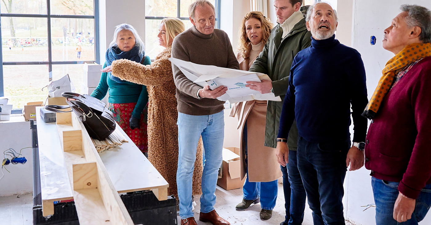 ouderen langer zelfstandig wonen. Groep ouderen gaan gezamelijk kijken naar een aanbouw van een appartementen complex