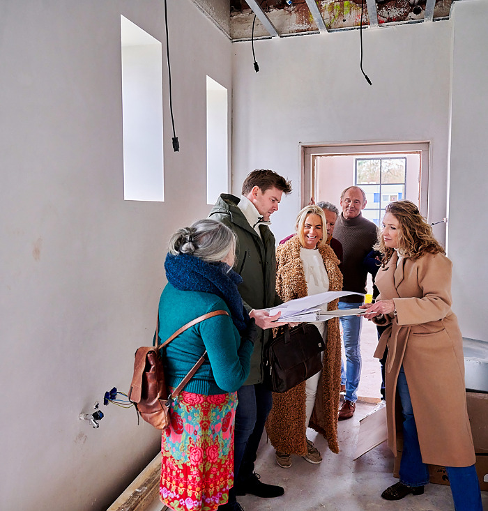 ouderen langer zelfstandig wonen. Groep ouderen gaan gezamelijk kijken naar een aanbouw van een appartementen complex