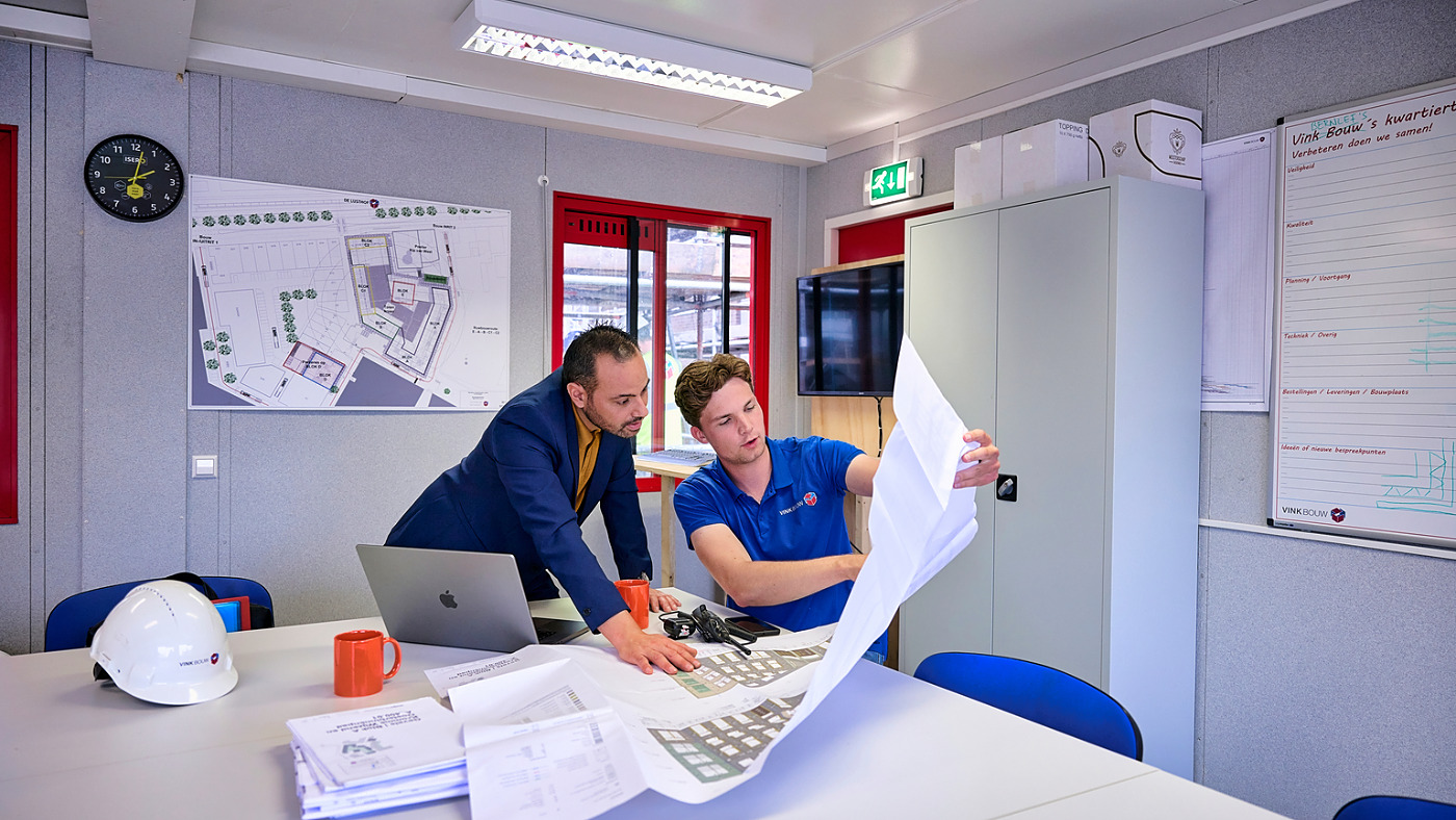 Collega's van het aannemers kantoor bespreken een bouwtekening