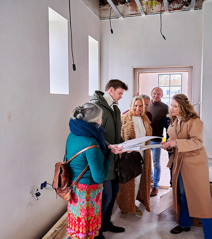 ouderen langer zelfstandig wonen. Groep ouderen gaan gezamelijk kijken naar een aanbouw van een appartementen complex